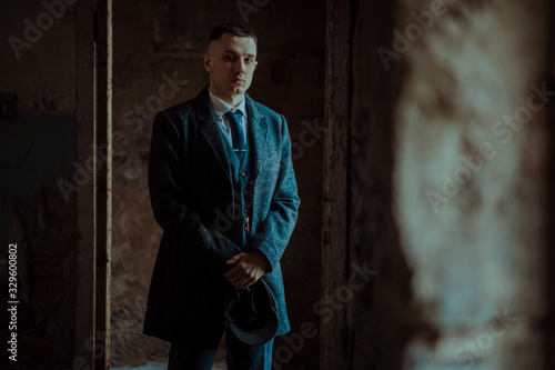 A man posing in the image of an English retro gangster in Peaky blinders style. photo