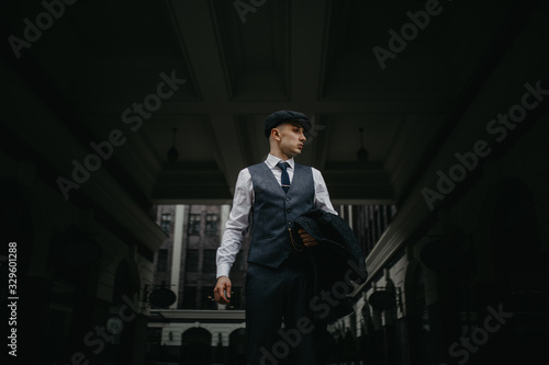 Canvas Print A man posing in the image of an English retro gangster in Peaky blinders style at city street