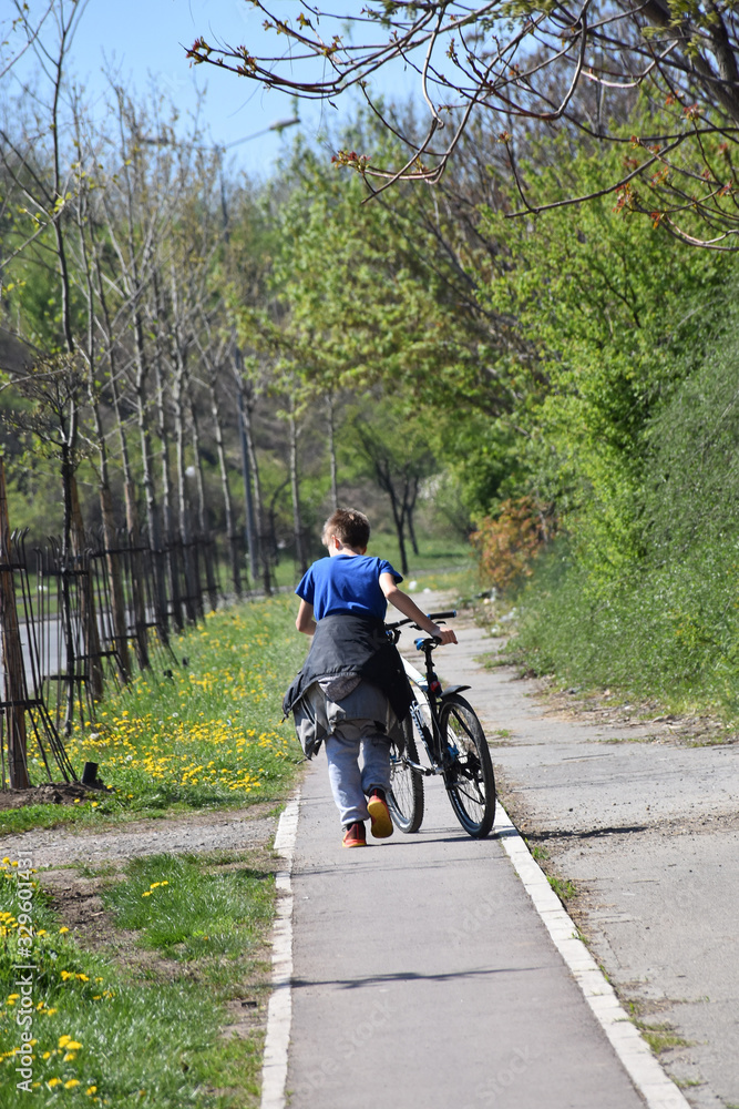 Naklejka premium A boy with a bike on a bike path by the side of the road