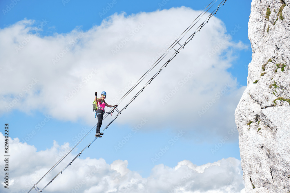 Stairway to heaven concept with a female climber holding her fist up and tight, on the via ferrata ladder at Intersport Klettersteig Donnerkogel route in Austria.