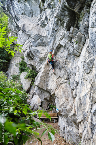 Woman starting to climb a difficult via ferrata route called Zimmereben (rated D/E), near Mayrhofen, Zillertal valley, Austria, with impressive rock formations around.
