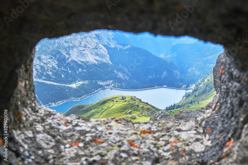 Fedaia Lake in Dolomites mountains, Italy, as seen through a crenel from an old war tunnel.