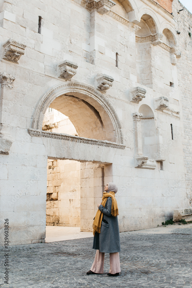 portrait of young European Muslim women with hijab exploring old city of Split as tourist. Diocletian's palace. 