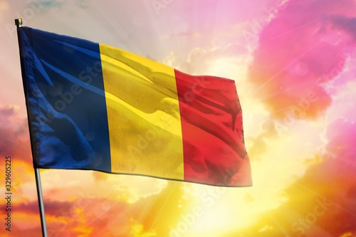 Fluttering Romania flag on beautiful colorful sunset or sunrise background. Success concept.