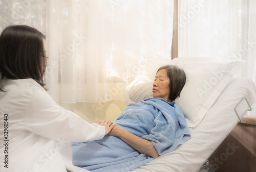 A doctor visits the old asian patient in the ward in the hospital