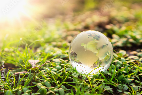 globe glass on green grass with sunshine background. environment concept