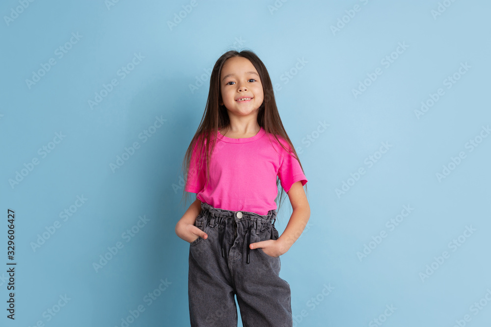 Posing confident. Caucasian little girl's portrait on blue studio background. Beautiful, cute female model in pink shirt. Concept of human emotions, facial expression, sales, ad, youth, childhood. Posing confident. Caucasian little girl's portrait on blue studio background. Beautiful, cute female model in pink shirt. Concept of human emotions, facial expression, sales, ad, youth, childhood.