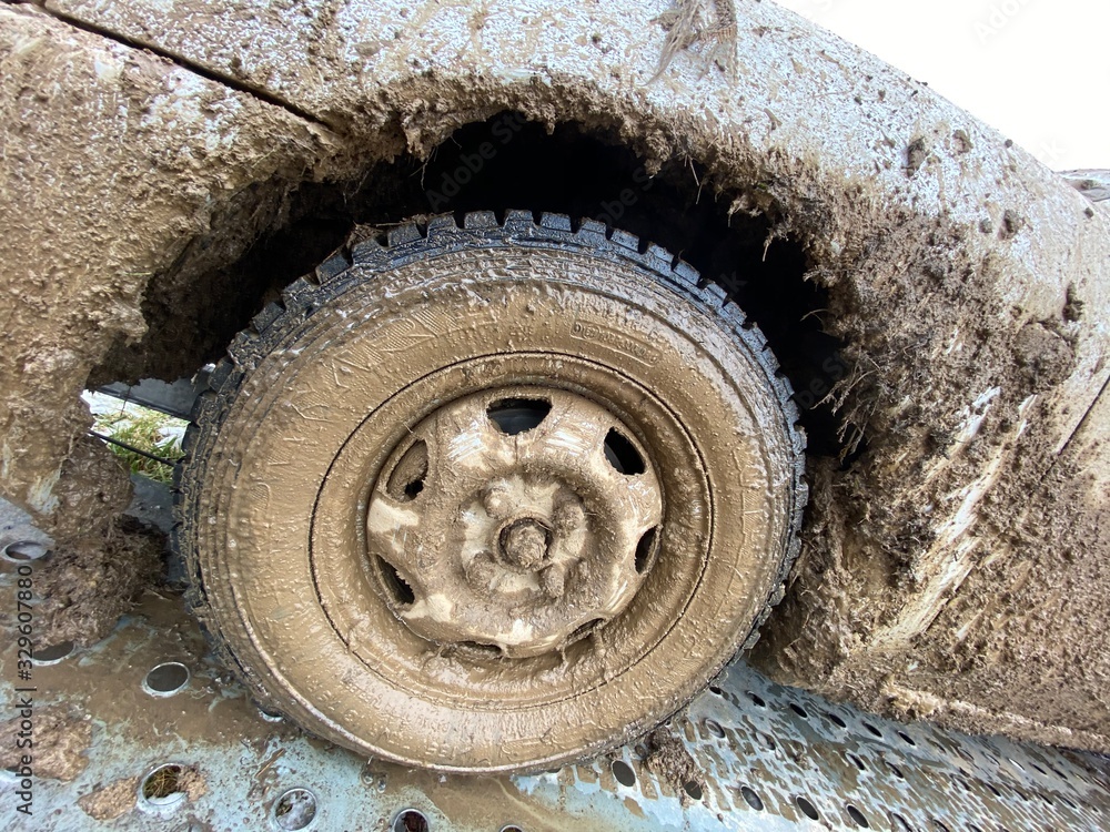 The detail of the car completely dirty by mud after the drag race on a field during winter. It needs complete cleaning of the exterior and interior. 