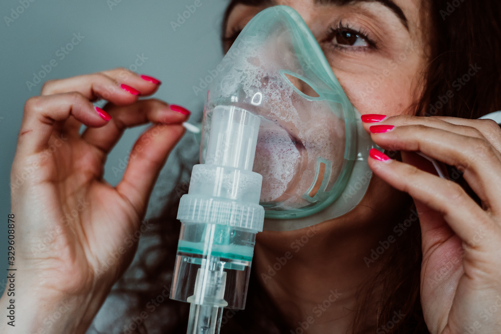 Young woman with weak health using assisted breathing at home. Treatment of a respiratory disease such as bronchitis or pneumonia. Coronavirus - obrazy, fototapety, plakaty 