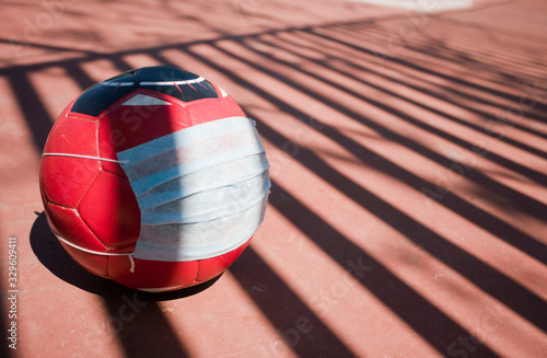 coronavirus concept in sport, soccer ball with breathing mask, soccer field photo