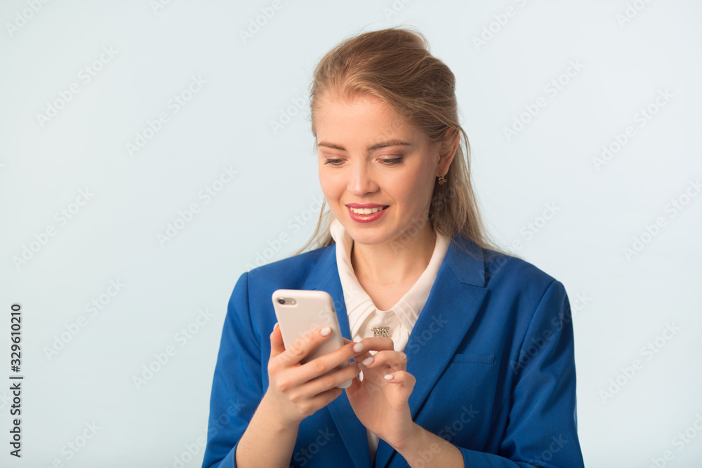 beautiful young woman in a blue jacket on a blue background with a phone in her hand beautiful young woman in a blue jacket on a blue background with a phone in her hand