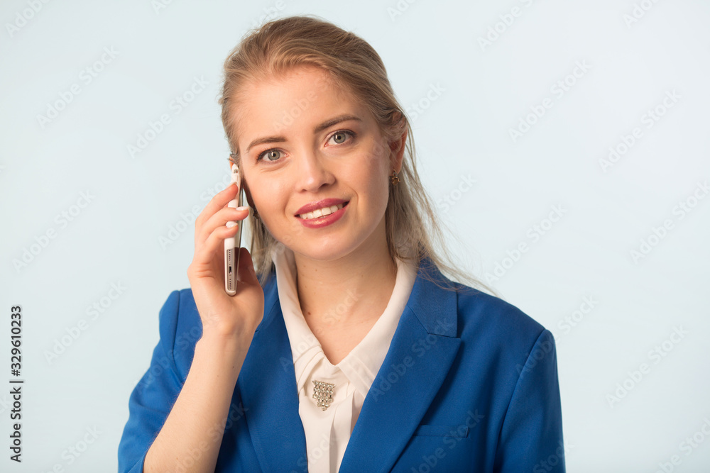 beautiful young woman in a blue jacket on a blue background with a phone in her hand beautiful young woman in a blue jacket on a blue background with a phone in her hand