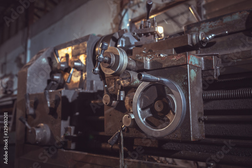 closeup of Old metallic lathe working against factory industrial interior background.