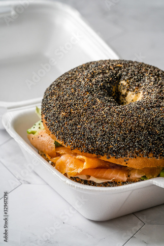 Take Away Salmon Bagel Sandwich with Lox Cream Cheese and Poppy Seeds in Plastic Container Box Package. photo