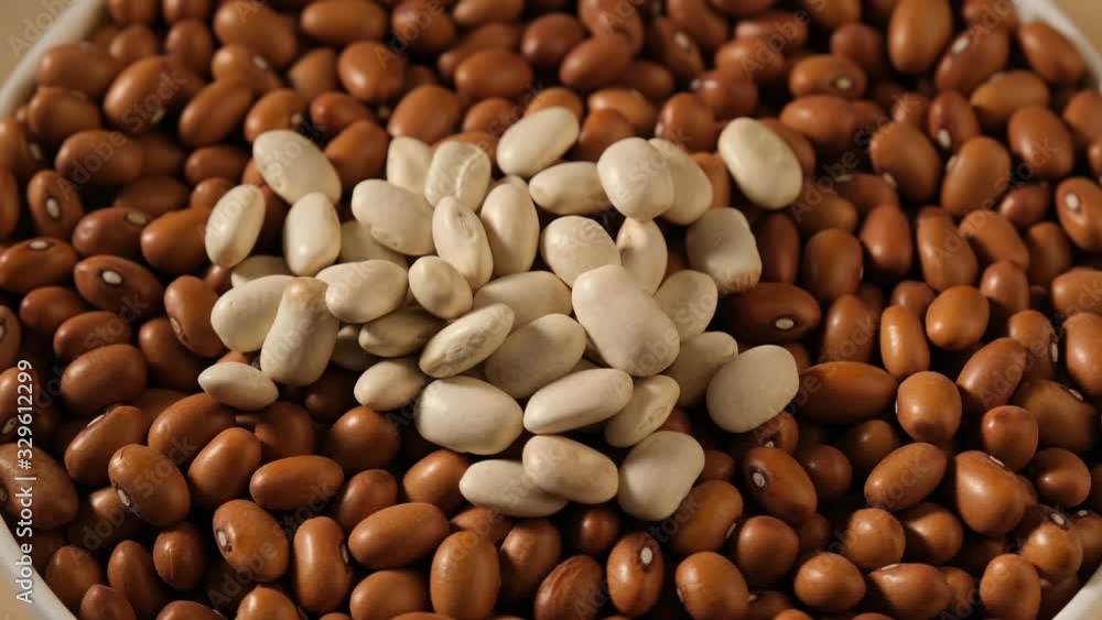 Dry uncooked white beans falling from spoon into bowl with kidney beans. Food video macro Dry uncooked white beans falling from spoon into bowl with kidney beans. Food video macro