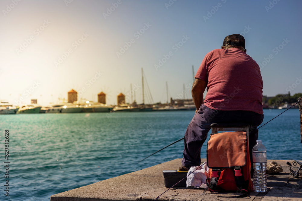 Fototapeta premium Fisherman in Rhodes, Greece. He is waiting for his prey.