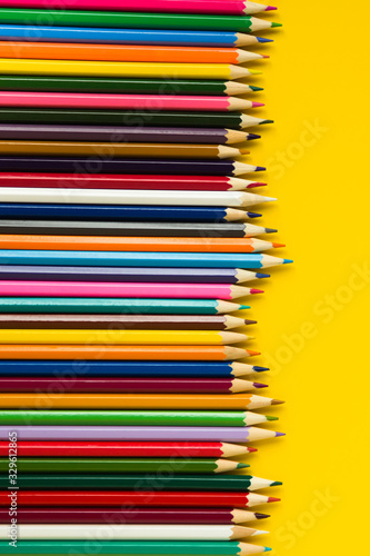 Colorful multicolor pencils on yellow background. flat lay top view copy space vertical layout