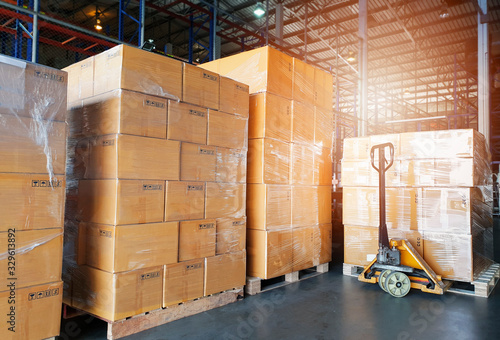 Interior of warehouse, stack package boxes on pallets and hand pallet truck, warehouse industry delivery shipment goods, logistics, transport