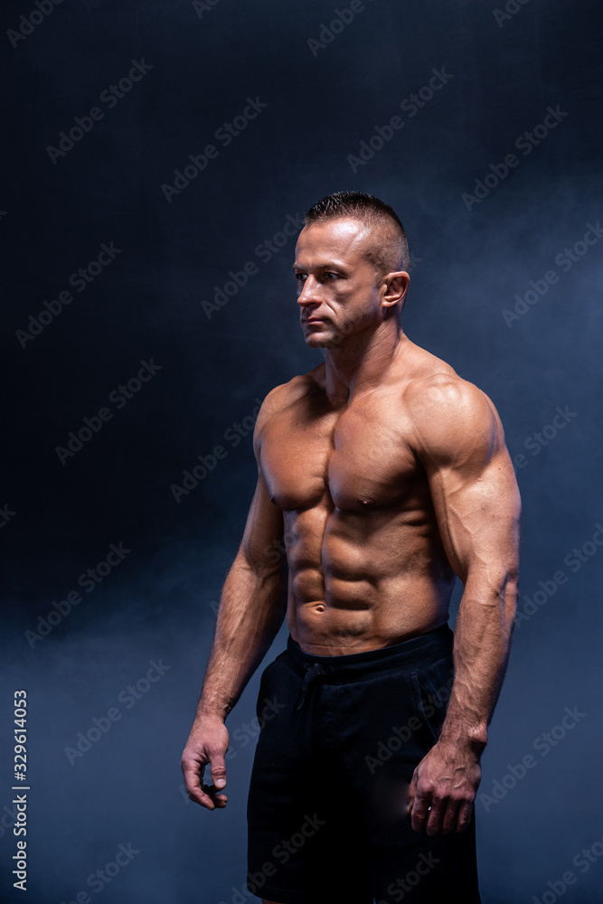Muscular man isolated on the black background. Strong male naked torso abs