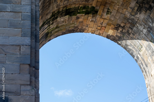 High Level Bridge supporting archway, made up of stone masonry and set against a contrasting beautiful blue sky.