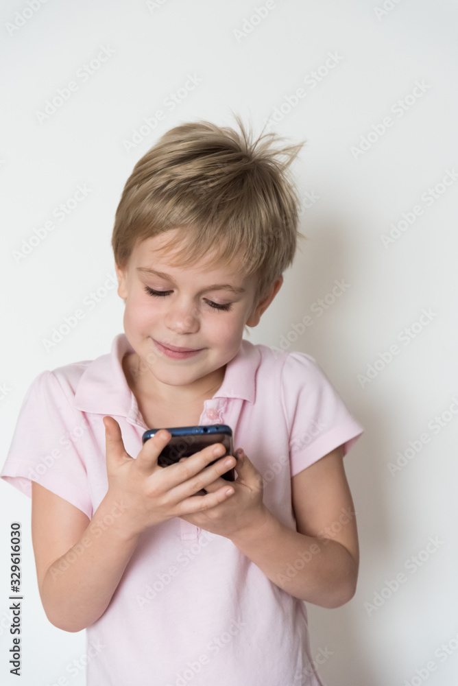 A cute little child looks at the phone screen and smiles sheepishly. A cute little child looks at the phone screen and smiles sheepishly.