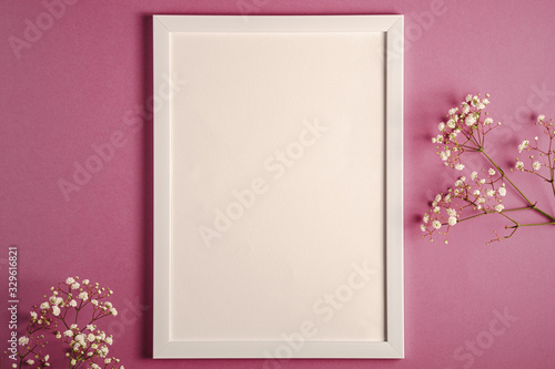 White picture frame with empty template, gypsophila flowers and fabric ribbon, pink purple pastel background, mockup card © Frostroomhead