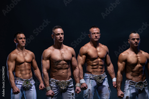 Four muscular man standing shirtless on black background. Concept of health, strength and power