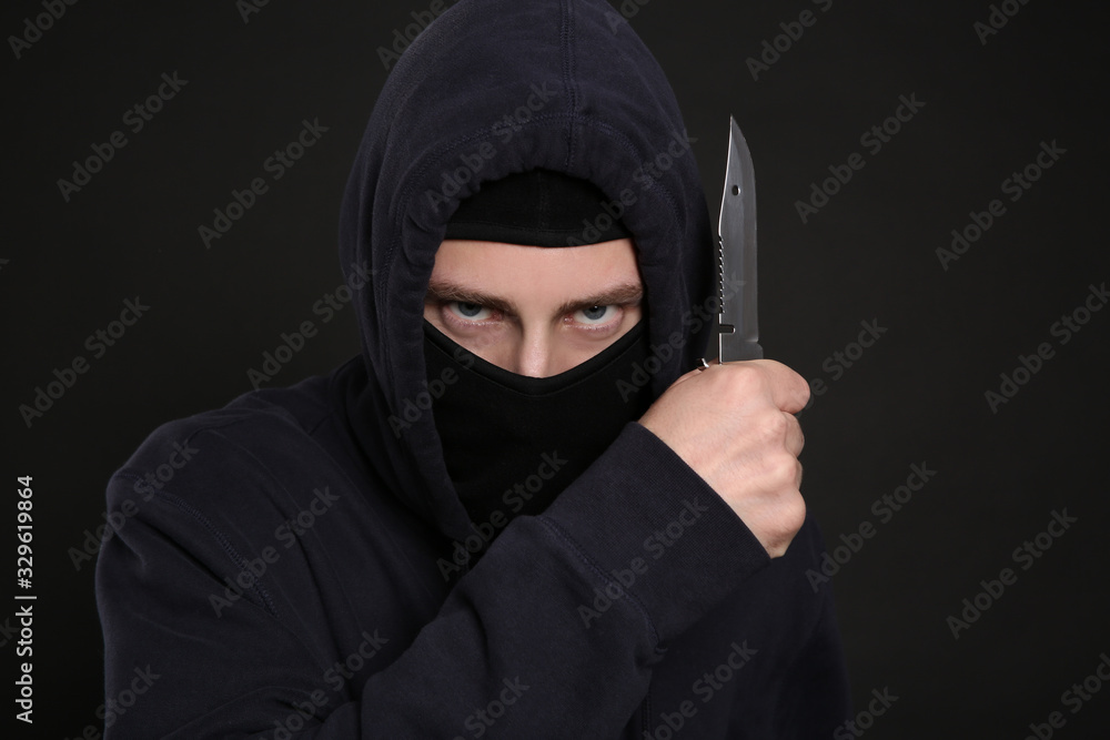Man in mask with knife on black background. Dangerous criminal Man in mask with knife on black background. Dangerous criminal