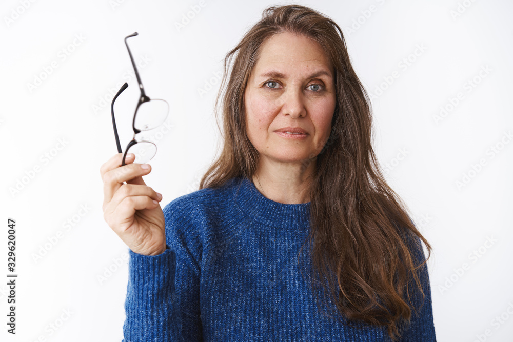Woman finished reading giving eyes rest, taking of glasses and holding eyewear in hand as looking at camera, having problems with sight, attending optician pick new pair over white background Woman finished reading giving eyes rest, taking of glasses and holding eyewear in hand as looking at camera, having problems with sight, attending optician pick new pair over white background