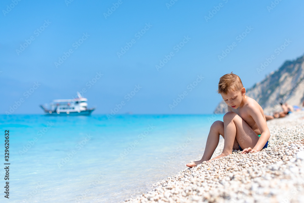 A boy is playing by the water on the beach A boy is playing by the water on the beach
