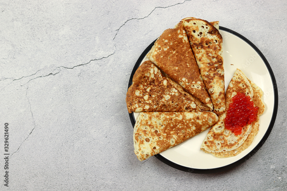 Pancakes with caviar in a plate on a light background. Top view, flat lay. Pancakes with caviar in a plate on a light background. Top view, flat lay.