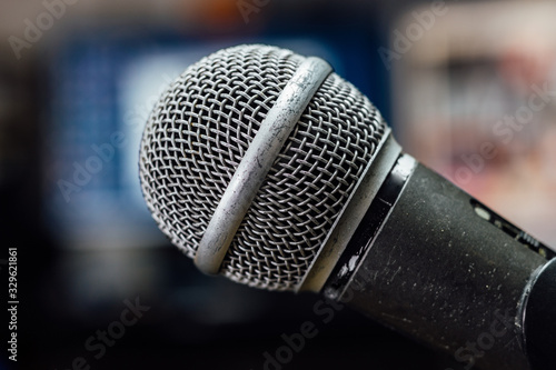 Old, scratched and used microphone on a stand in a studio. Blurred background, close up. 