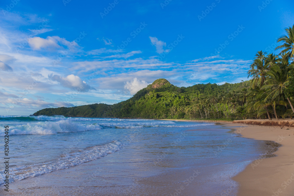 empty sand beach with waves and sun covered with cloudy sky and tropical trees on background in El Nido, Palawan province, Philippines empty sand beach with waves and sun covered with cloudy sky and tropical trees on background in El Nido, Palawan province, Philippines