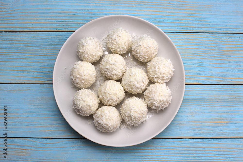 Round candies in coconut flakes lie in a plate
