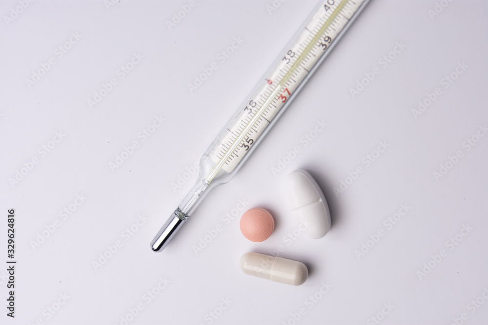 thermometer pills and tablets lying scattered on white isolated background thermometer pills and tablets lying scattered on white isolated background