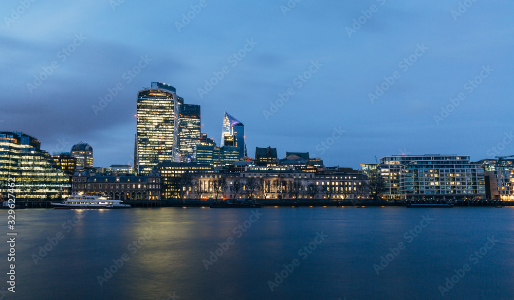 Naklejka premium View of London downtown skyline with skyscrapers reflection in river Thames. Long exposure blue hour shot.