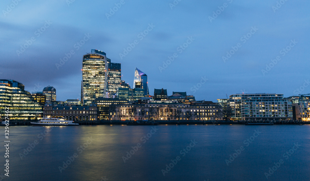 View of London downtown skyline with skyscrapers reflection in river Thames. Long exposure blue hour shot.