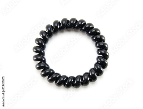 One black spiral elastic for hair on a white isolated background. A flexible plastic item for a female hairstyle or an arm bracelet. Elastic accessory