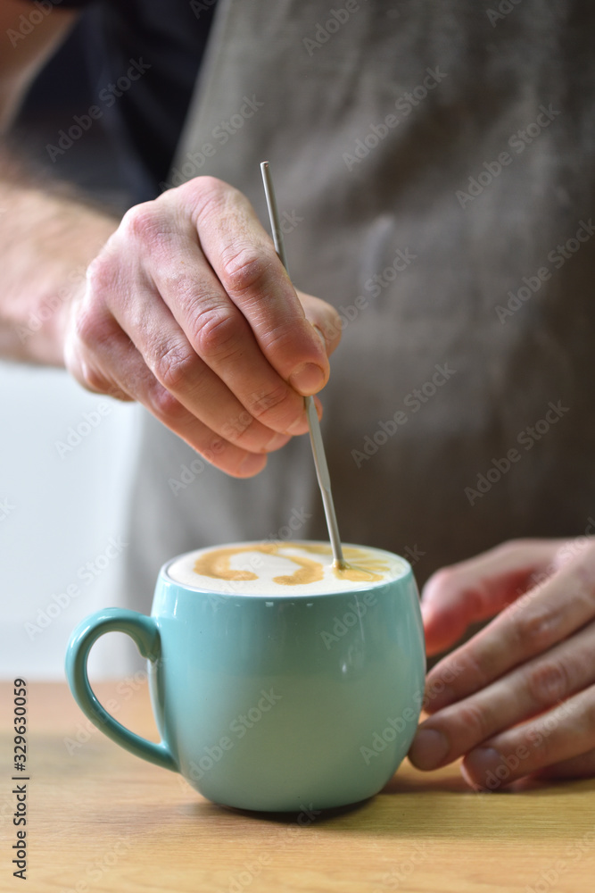 Bartender in a coffee shop, creates a picture while making coffee, closeup Bartender in a coffee shop, creates a picture while making coffee, closeup
