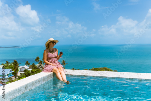 A beautiful woman is relaxing in a rich villa with a pool with luxurious views of the sea and palm trees. Portraits of the face. Nice vacation. Exotic and tropics with a girl.