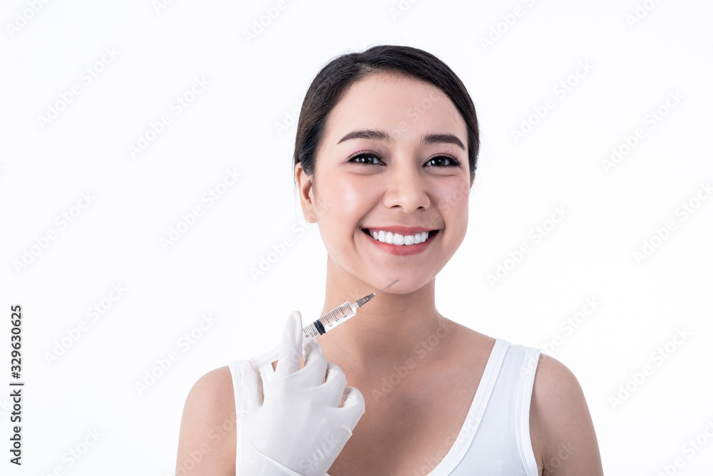 Portrait images of Asian pretty young woman, smiling, beautiful white and clean teeth And syringe placed on the face Ready for injection On white background to people and Cosmetic surgery concept. Portrait images of Asian pretty young woman, smiling, beautiful white and clean teeth And syringe placed on the face Ready for injection On white background to people and Cosmetic surgery concept.