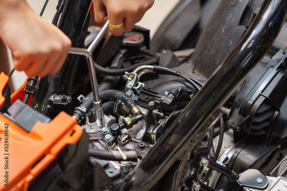 Mechanic using a wrench and socket on the engine of a motorcycle , selective focus Mechanic using a wrench and socket on the engine of a motorcycle , selective focus