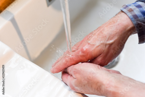Wash hands with soap to prevent spread of germs Male hands washing in the sink