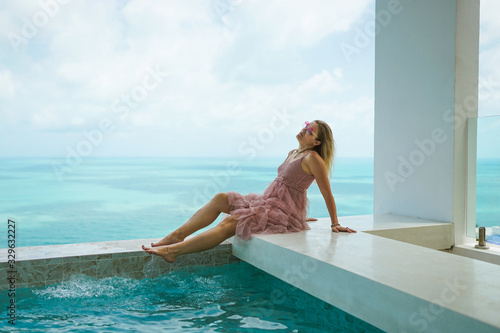 A beautiful woman is relaxing in a rich villa with a pool with luxurious views of the sea and palm trees. Portraits of the face. Nice vacation. Exotic and tropics with a girl. © Underwater girls