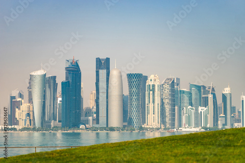 Panoramic view of modern skyline of Doha with green grass foreground. Concept of healthy environment