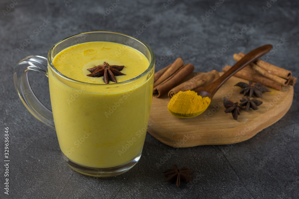 Fototapeta premium A set of spices for the preparation of golden milk and a cup of golden milk on a dark background.