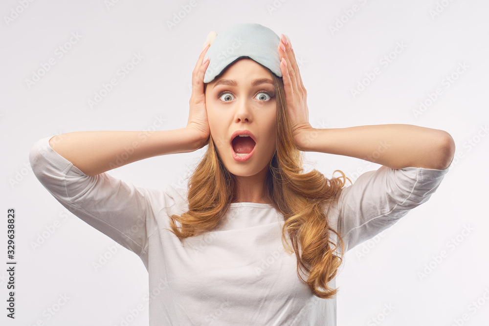 A cheerful energetic girl with long curly hair opens her mouth in shock, holds her head with her hands, and is shocked that she overslept. The concept of a positive good morning and healthy sleep. A cheerful energetic girl with long curly hair opens her mouth in shock, holds her head with her hands, and is shocked that she overslept. The concept of a positive good morning and healthy sleep.