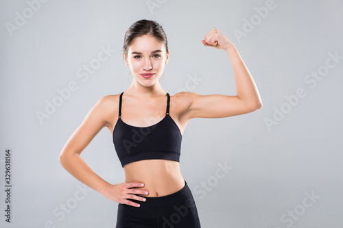 Portrait of a beautiful fitness woman showing her biceps on a white background