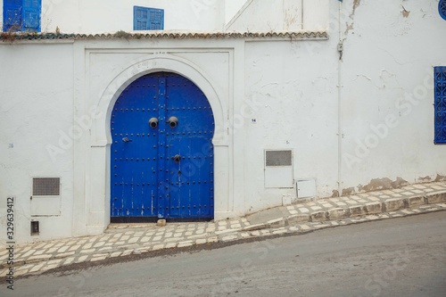 Blue doors in a white wall, the entrance to the house on a sloping street in the city of Sidi bou Said