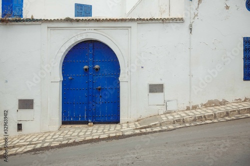 Blue doors in a white wall, the entrance to the house on a sloping street in the city of Sidi bou Said © yakovenko